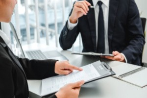 eBen HR administration consultant showing HR guidelines to an employer from a clipboard