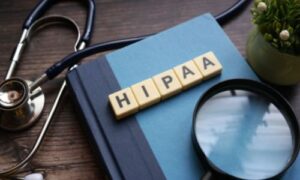 Word HIPAA made from alphabet dices are placed on a book and a stethoscope is placed next to the book