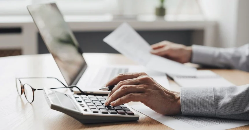 Person-with-Calculator-and-Laptop-and-Paperwork-1200-627