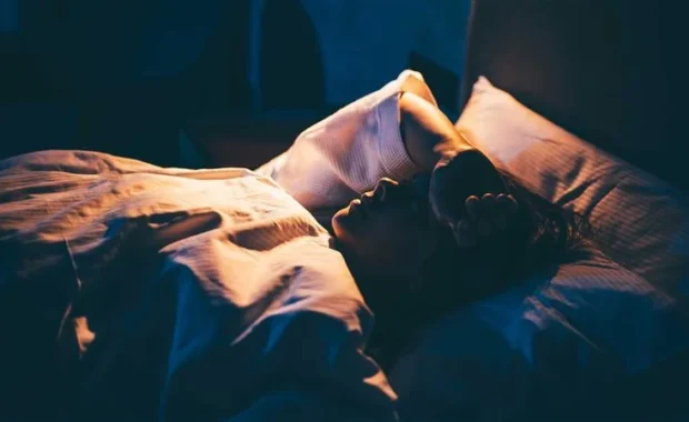 Woman-with-Insomnia.-Young-woman-lying-on-bed-with-hand-on-forehead