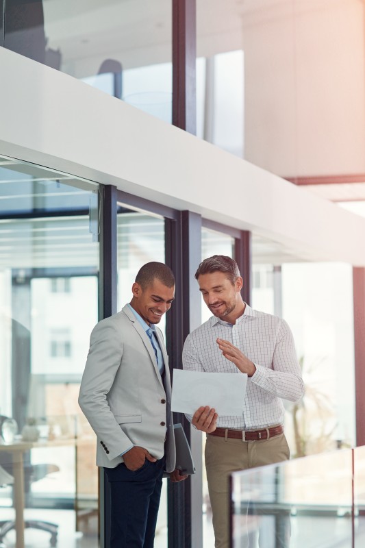 Business, men and meeting with document in office for real estate, property planning and web listing. People, realtor and paperwork for auction, viewing agenda and information for resale opportunity.